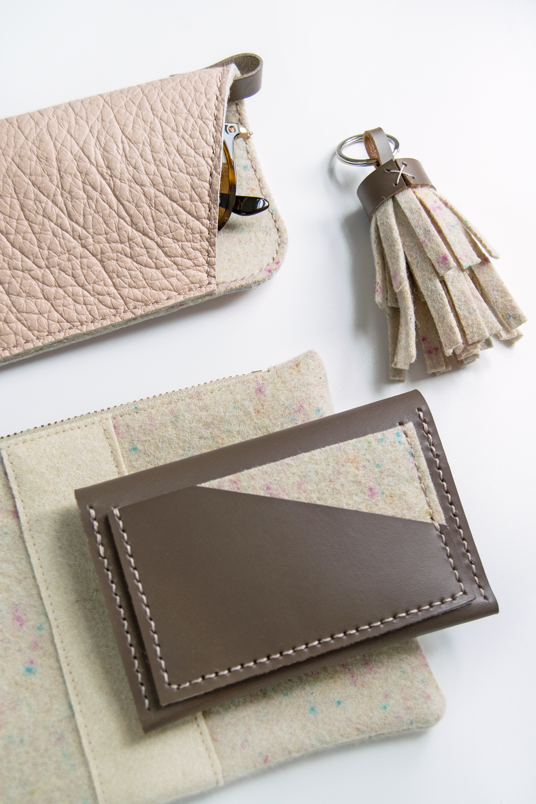 Blush leather glasses sleeve paired with confetti tassel keychain, confetti zip pouch and taupe leather card holder.